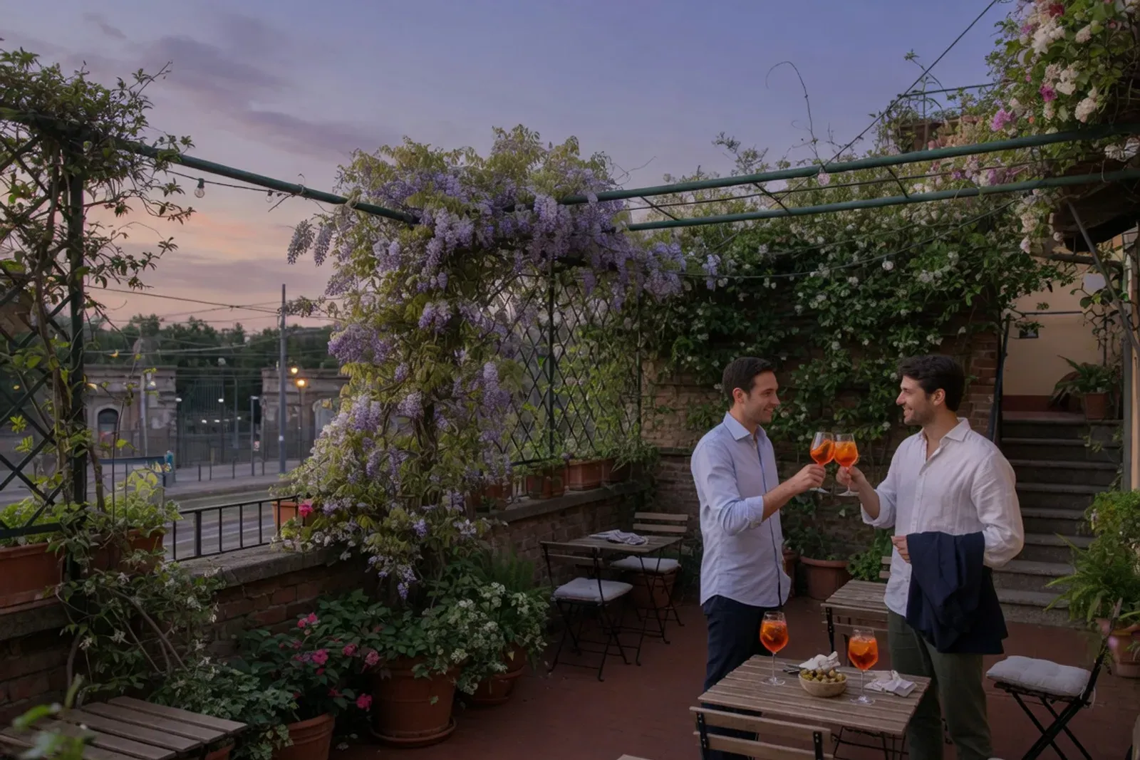 Jardin-terrasse d'un hôtel de Porta Venezia au crépuscule : tables basses, plantes grimpantes, deux hommes qui trinquent avant de sortir.