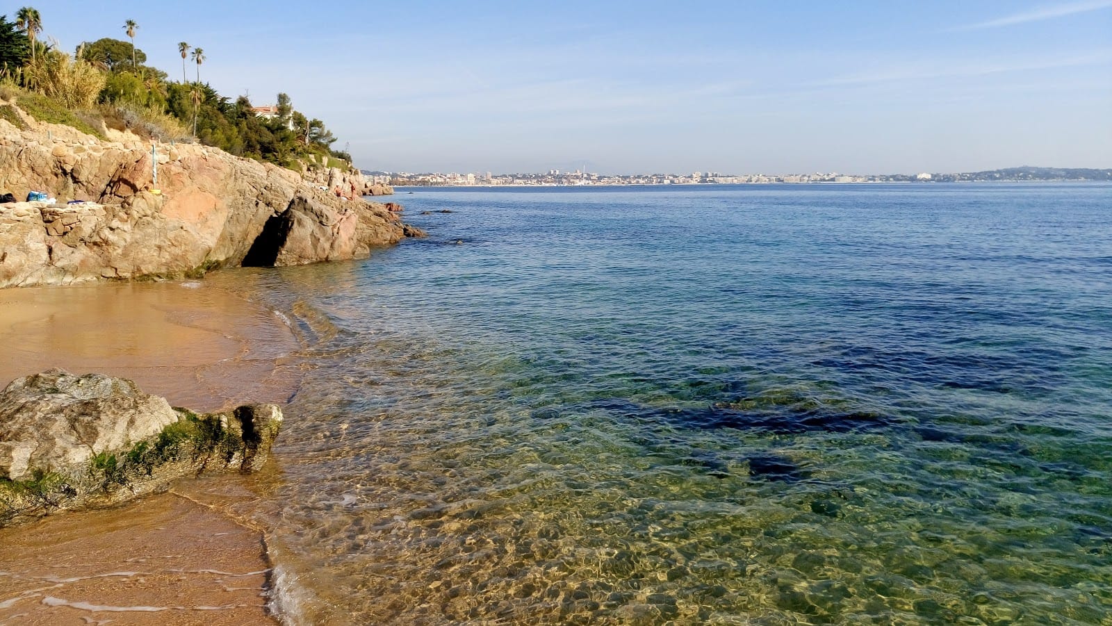 Crique de galets bordée de rochers et de pins sur le littoral entre Cannes et Golfe-Juan.