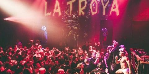Une foule de personnes dans une boîte de nuit avec le mot la troya.