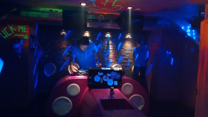 Un homme joue un DJ dans une salle rose vibrante pendant la vie nocturne gay d'Amsterdam.