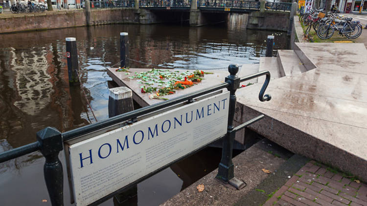 Un signe sur le côté d'un canal à Amsterdam orné de fleurs éclatantes.