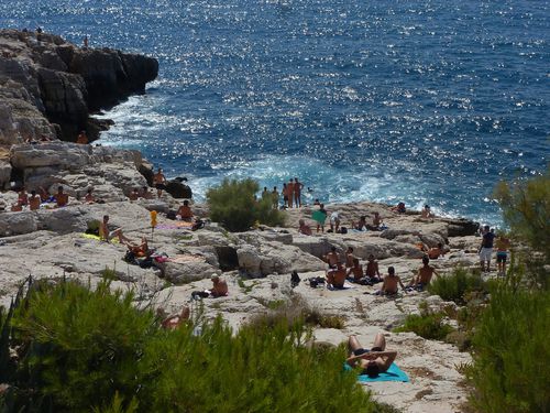 Un groupe de personnes est assis sur une falaise rocheuse surplombant l'océan à Marseille.