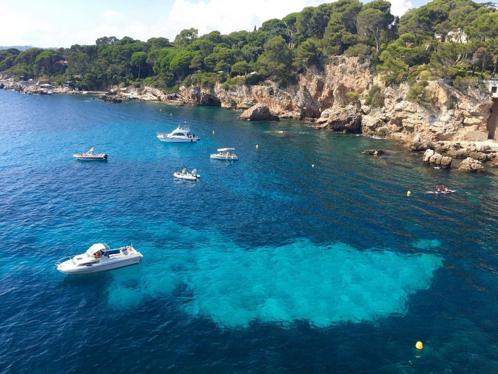 Un groupe de bateaux amarrés près d'un rivage rocheux sur la Côte d'Azur.