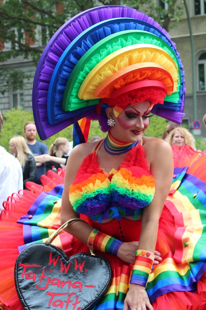 Une femme dans un costume arc-en-ciel vibrant s'exprimant pendant la vie nocturne gay animée de Berlin.