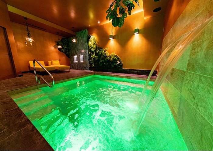 Une piscine intérieure avec un éclairage vert vif et une cascade captivante à Marseille gay-friendly.