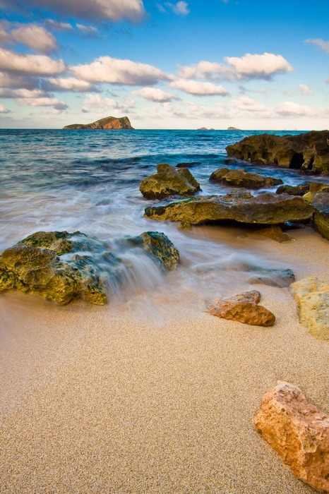 Une plage pittoresque avec des rochers et de l'eau offrant une ambiance de fête sur l'île la plus festive d'Espagne, Ibiza.