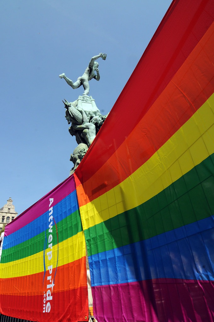 Un drapeau LGBTQ+ près d'une statue à Anvers représentant la scène gay dynamique de la ville, sa vie nocturne, sa culture et ses événements.