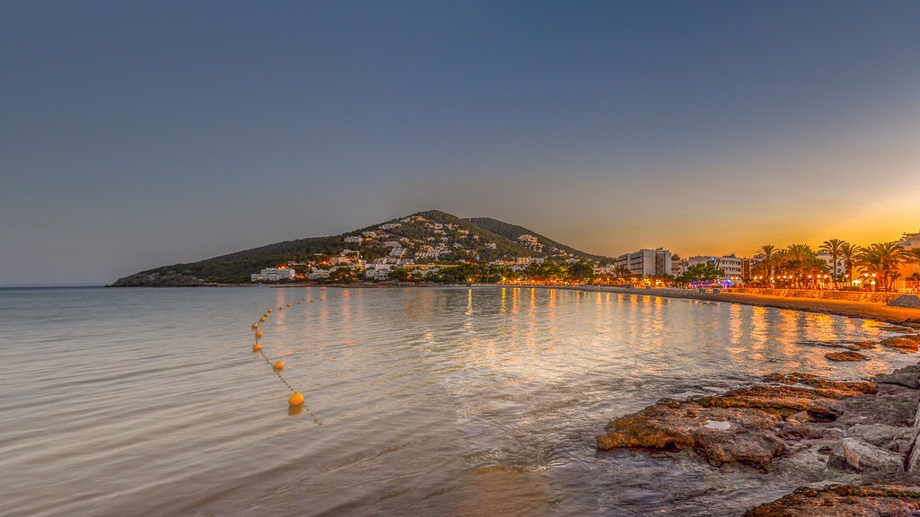 Une plage festive au crépuscule avec une montagne en arrière-plan sur l'île animée d'Ibiza.