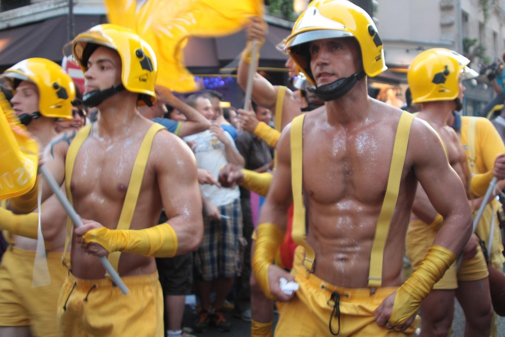 Un groupe d'hommes vêtus de jaune célèbre joyeusement lors du défilé de la fierté française en 2023.