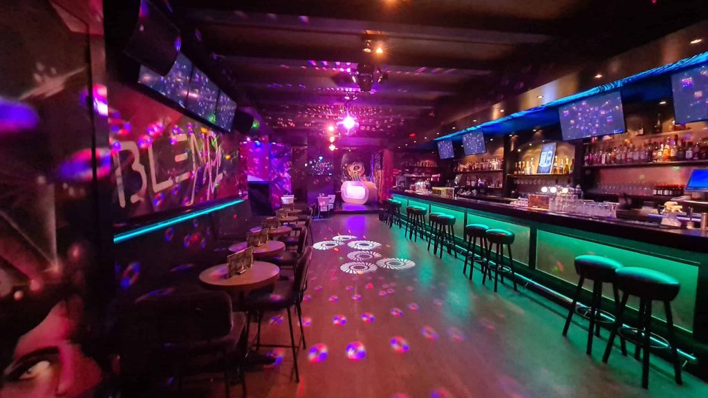 Une discothèque LGBTQ+ d'Amsterdam avec des lumières néon et un bar.