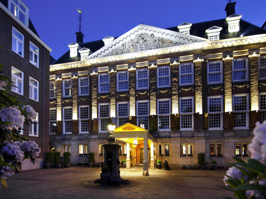 Un grand bâtiment est illuminé la nuit à Amsterdam.