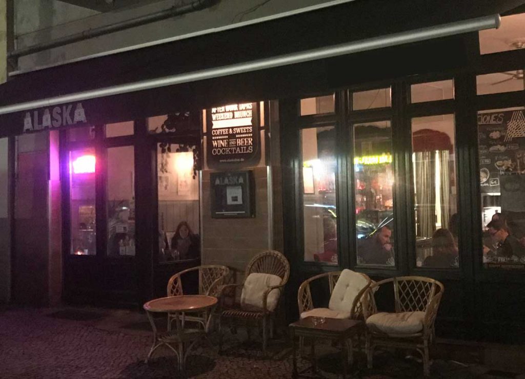 Un guide gay de Berlin menant à un restaurant en plein air avec des tables et des chaises la nuit.