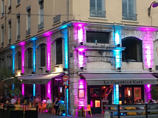 Un bar convivial LGBTQIA+ aux lumières vibrantes sur le côté de l'immeuble à Lyon.