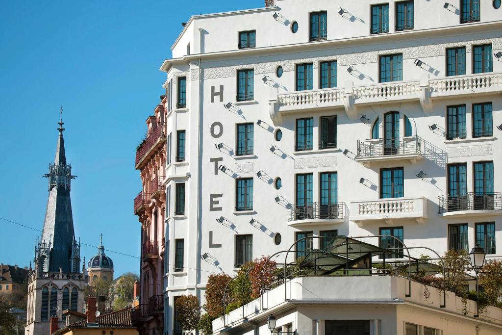 Un bâtiment blanc avec le mot hôtel dessus, servant de guide aux voyageurs Gay à Lyon.