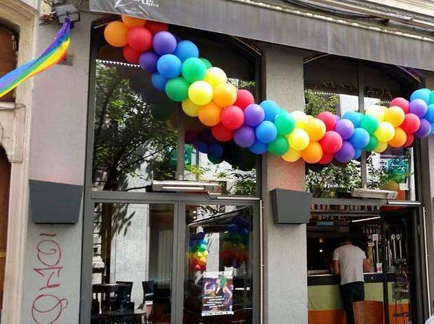 Ballons arc-en-ciel suspendus à l'extérieur d'un restaurant à Lyon, un guide pour la communauté gay.
