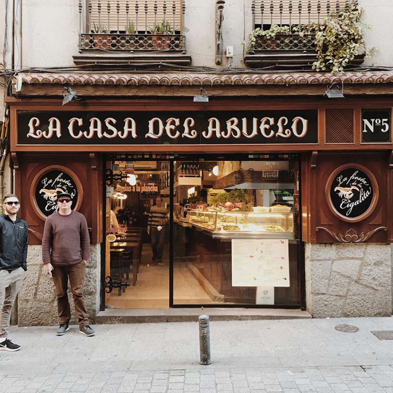 Deux hommes debout devant une boulangerie à Barcelone tout en profitant des meilleurs bars à tapas de Madrid.