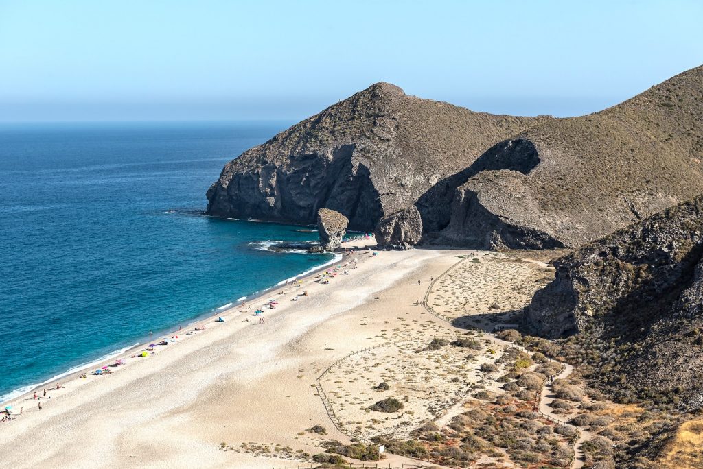 Une vue aérienne d'une plage avec des falaises en arrière-plan, idéale pour les voyageurs gays explorant les superbes côtes européennes.