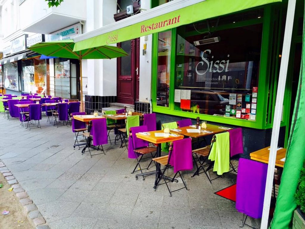 Un restaurant cher Guide gay Berlin avec des tables et des chaises sur un trottoir.