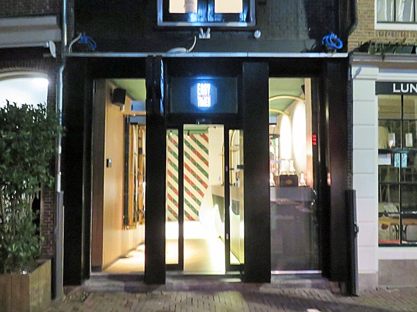 Une entrée de restaurant illuminée la nuit à Amsterdam, parfaite pour les voyageurs gays.