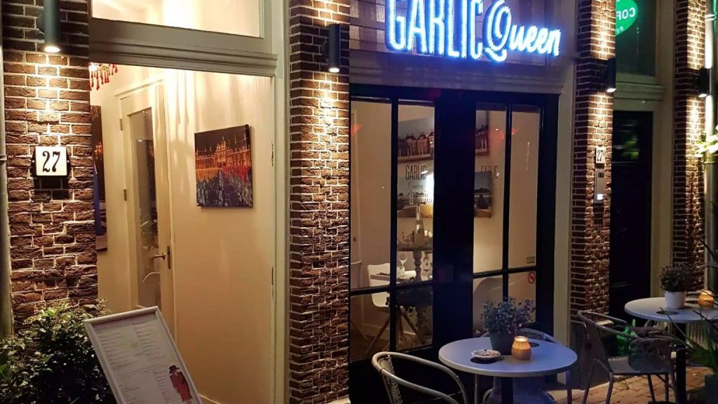 Un restaurant gay-friendly en Europe avec des tables et des chaises devant un bâtiment en briques.