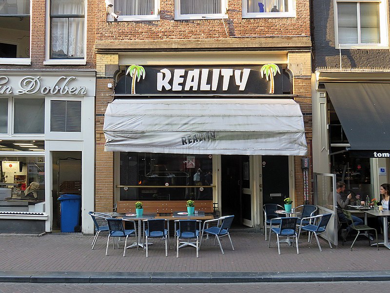 Un restaurant gay-friendly avec tables et chaises sur le côté d'une rue - Guide de voyage gay à Amsterdam.