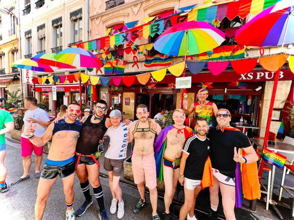 Un groupe d'amis gays posant devant un bar.