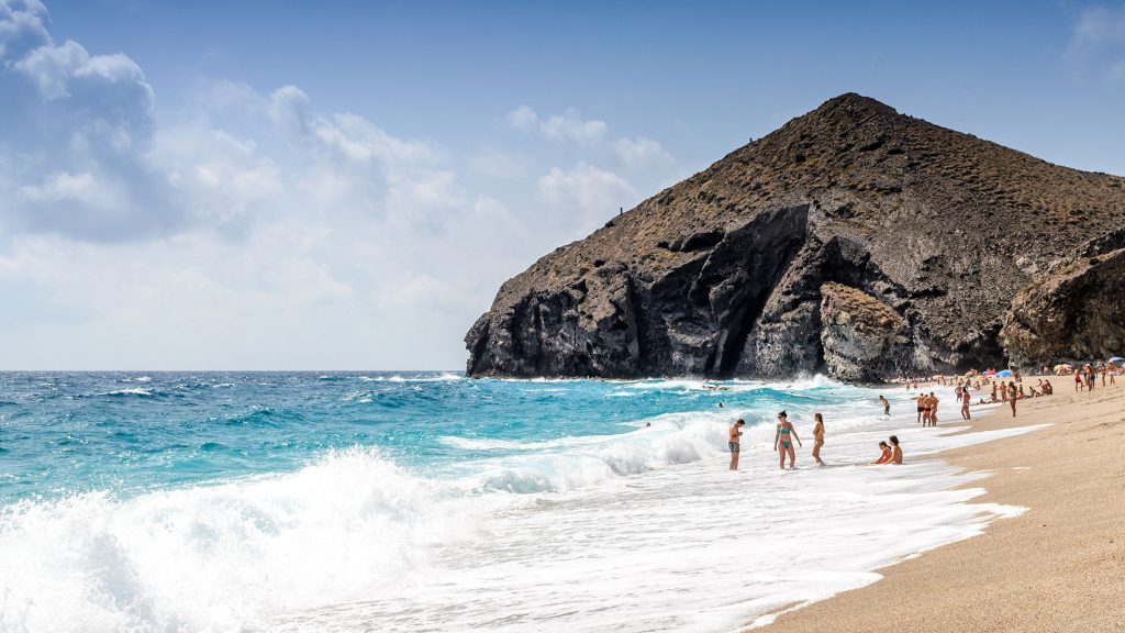 Un groupe de personnes sur une plage près d'une falaise rocheuse dans l'une des meilleures plages gay d'Espagne.