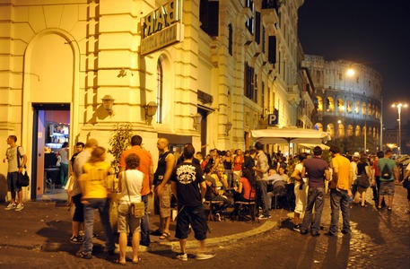 Une foule de personnes debout devant un immeuble à Rome la nuit.