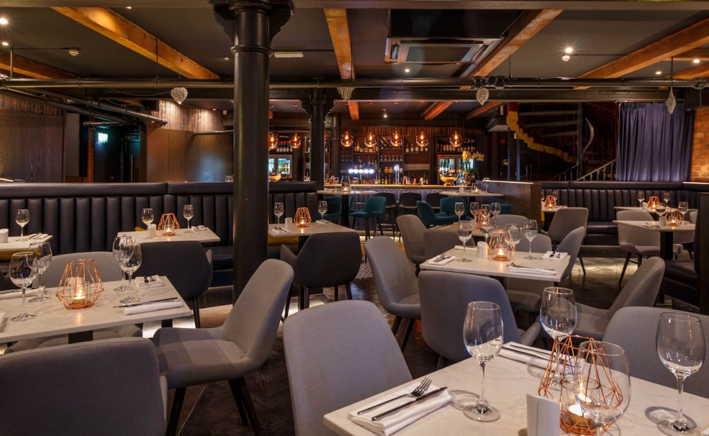 Un restaurant avec tables et chaises installés dans une pièce sombre à Manchester.
