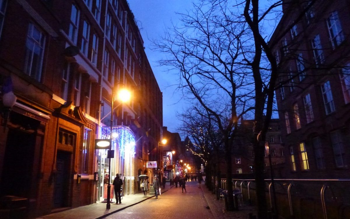 Une rue conviviale LGBTQ+ bordée de bâtiments en briques au crépuscule dans Canal Street à Manchester.