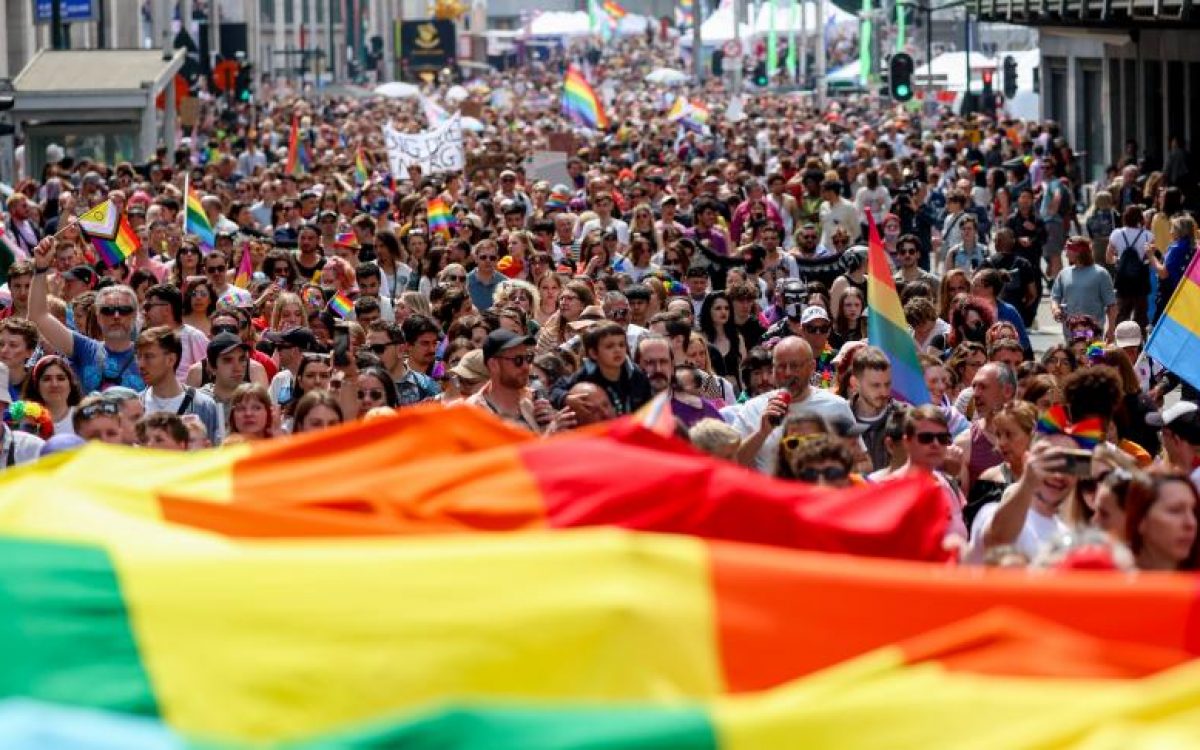 Une foule de personnes marchant dans une rue avec des drapeaux arc-en-ciel à Bruxelles Pride 2023.
